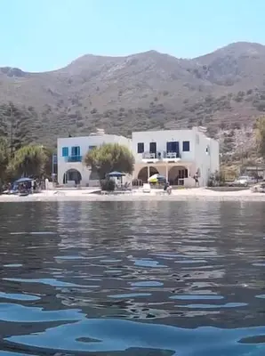 a couple of white buildings sitting on the water at Pavlos Rooms in Livadia