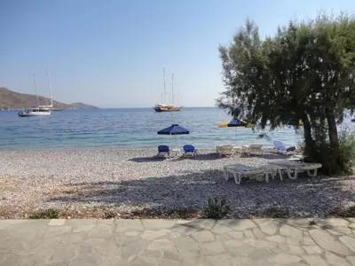 a beach with chairs and umbrellas and the water at Pavlos Rooms in Livadia
