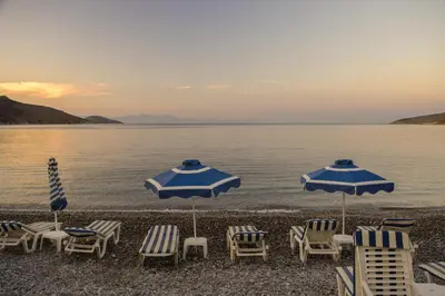 a group of chairs and umbrellas on a beach at Pavlos Rooms in Livadia