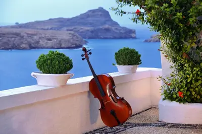 a violin sitting on a wall next to potted plants at Villa Melenos Lindos in Líndos