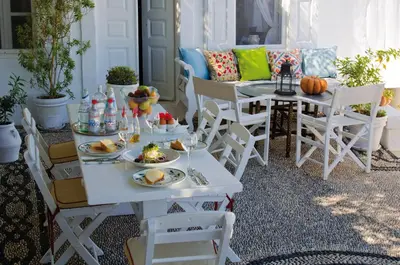 a porch with a table and chairs with food on it at Villa Melenos Lindos in Líndos