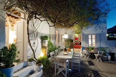 a patio with a table and chairs and a tree at Villa Melenos Lindos in Líndos