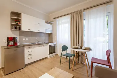 a kitchen with white cabinets and a table and chairs at Serenity Studio for couples in Rhodes Town