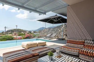 a patio with a couch and an umbrella and a pool at Villa Katerina in Líndos