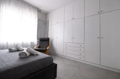 a bedroom with white cabinets and a bed and a chair at Luxury spacious apartment in the heart of the city in Rhodes Town