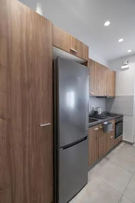 a kitchen with a stainless steel refrigerator and wooden cabinets at Luxury spacious apartment in the heart of the city in Rhodes Town