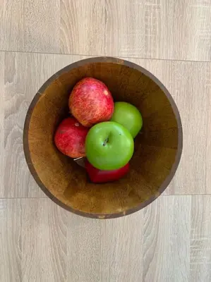 a wooden bowl filled with apples on a wooden table at Luxury spacious apartment in the heart of the city in Rhodes Town