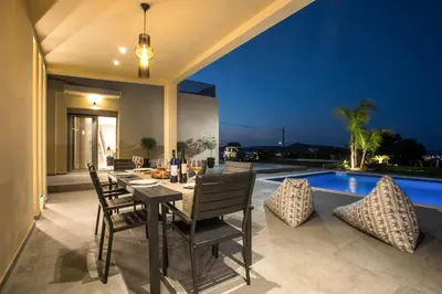 a dining room with a table and chairs and a pool at Madi Villa in Faliraki