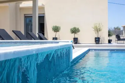 a swimming pool with chairs next to a house at Madi Villa in Faliraki