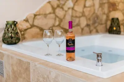 a bottle of wine and two wine glasses on a bath tub at ALMI Traditional House in Koskinou