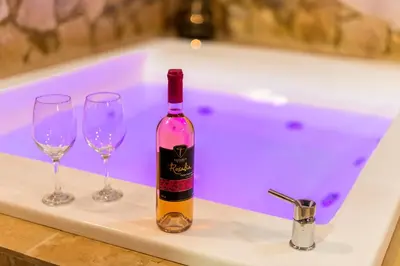 a bottle of wine and two wine glasses on a bath tub at ALMI Traditional House in Koskinou