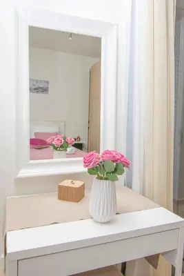 a vase with pink flowers on a table in front of a mirror at Haraki Villas in Haraki