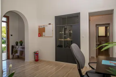a living room with a black cabinet and a chair at Monte Smith Luxury Garden Apartment With Parking in Rhodes Town