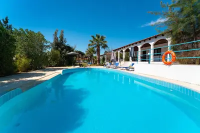 a swimming pool with blue water in front of a house at Villas Mina and Studios in Gennadi