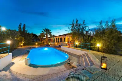 a swimming pool in front of a house at night at Villas Mina and Studios in Gennadi