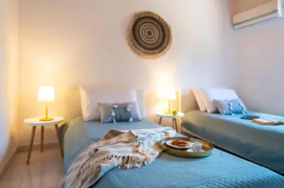 a room with two beds and two tables with lamps at Villas Mina and Studios in Gennadi