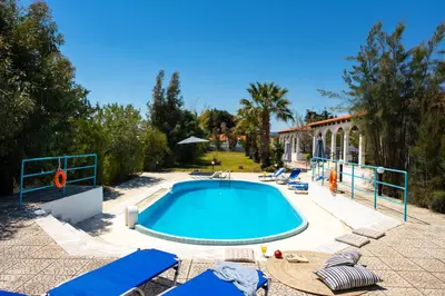 a swimming pool with lounge chairs and a resort at Villas Mina and Studios in Gennadi
