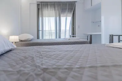 a white bedroom with two beds and a window at Demiani House in Lardos