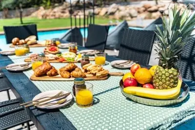 a table with food and fruit on it next to a pool at Kallithea Residence in Koskinou