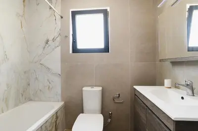 a bathroom with a toilet and a sink and a window at Green Villa in Ialyssos