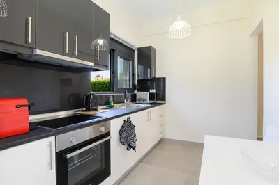 a kitchen with white cabinets and black appliances at Green Villa in Ialyssos