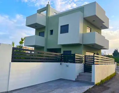 a house with a white fence in front of it at Green Villa in Ialyssos