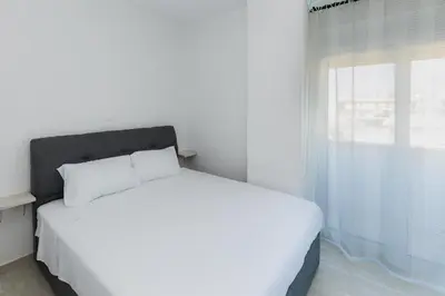 a white bed in a white bedroom with a window at Rhodes City Center Apartments in Rhodes Town