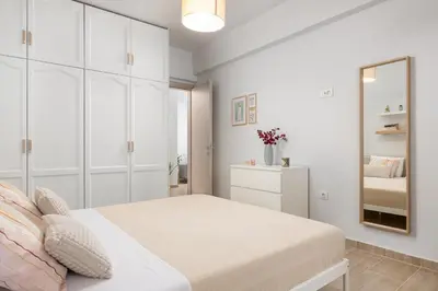 a white bedroom with a bed and a mirror at Klinon Asti city apartment in Rhodes Town
