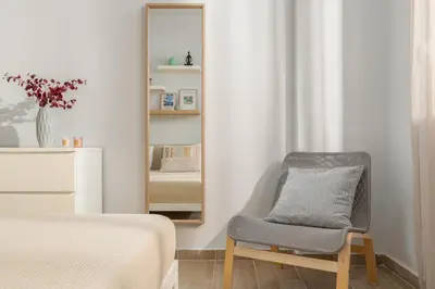 a bedroom with a chair in front of a mirror at Klinon Asti city apartment in Rhodes Town