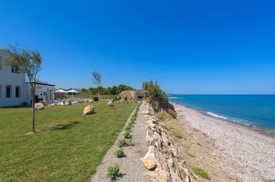 a retaining wall on a beach next to the ocean at Panaxia Villas in Theologos