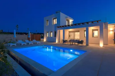 a villa with a swimming pool at night at Panaxia Villas in Theologos