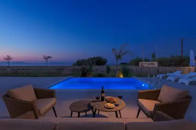a patio with a table and chairs next to a swimming pool at Panaxia Villas in Theologos