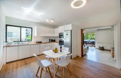 a kitchen with white cabinets and a table and chairs at flower veranda 1st floor app in Rhodes Town