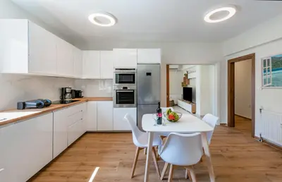 a kitchen with white cabinets and a white table and chairs at flower veranda 1st floor app in Rhodes Town
