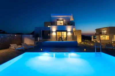 a villa with a swimming pool at night at Ventus Villas in Koskinou