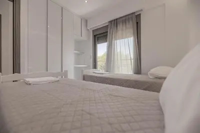 a white bedroom with two beds and a window at Diorisa House in Lardos
