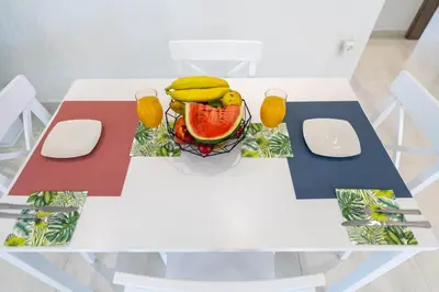 a white table with a bowl of fruit and glasses of juice at Diorisa House in Lardos