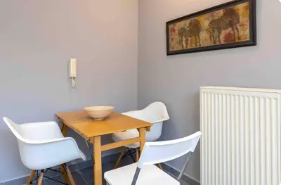 a table with white chairs and a radiator in a room at Verde Casa luxury apartment close to old town in Rhodes Town