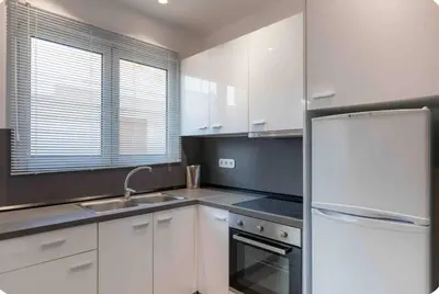 a kitchen with white cabinets and a stainless steel refrigerator at Verde Casa luxury apartment close to old town in Rhodes Town
