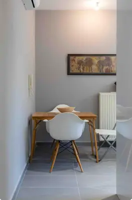 a dining room with a wooden table and a white chair at Verde Casa luxury apartment close to old town in Rhodes Town