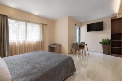 a bedroom with a bed and a desk and a television at Lampraki Luxury Apartments in Rhodes Town