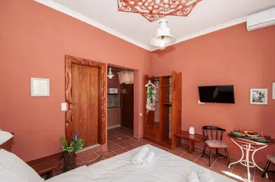 a bedroom with orange walls and a bed and a table at Tango Suites in Rhodes Town