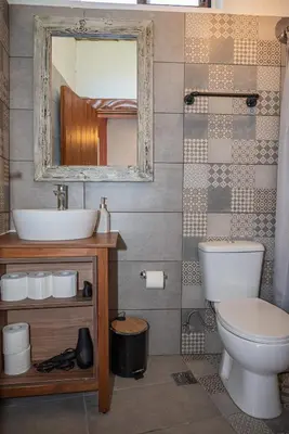 a bathroom with a toilet and a sink and a mirror at Tango Suites in Rhodes Town