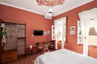 a bedroom with orange walls and a bed and a table at Tango Suites in Rhodes Town
