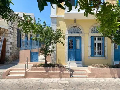 a yellow and blue building with blue doors at Arsanas in Symi