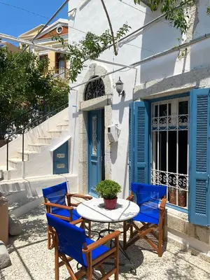 a table and chairs in front of a building with blue doors at Arsanas in Symi