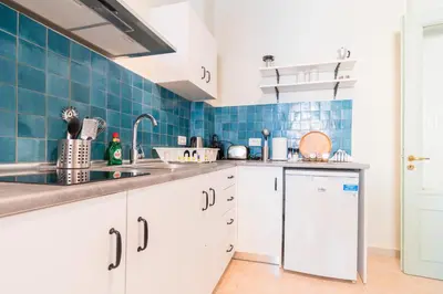 a kitchen with white cabinets and blue tiles at Arsanas in Symi