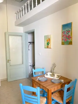 a dining room with a wooden table and blue chairs at Arsanas in Symi