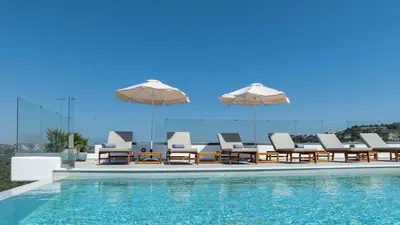 a swimming pool with lounge chairs and umbrellas at Agnanti Sea View Villa in Koskinou