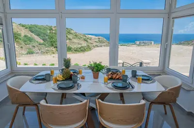 a dining room with a table and chairs and the ocean at Agnanti Sea View Villa in Koskinou
